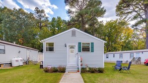 A single-story mobile home with a front porch, a small garden, and a clear sky.