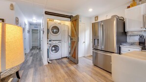 A modern kitchen with stainless steel appliances, a wooden floor, and a laundry area with a washing machine and dryer.
