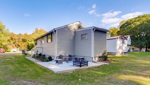 A two-story house with a front porch, a small deck, and a well-maintained lawn.