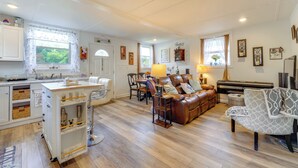 A spacious living area with a dining table, leather sofa, and a piano.