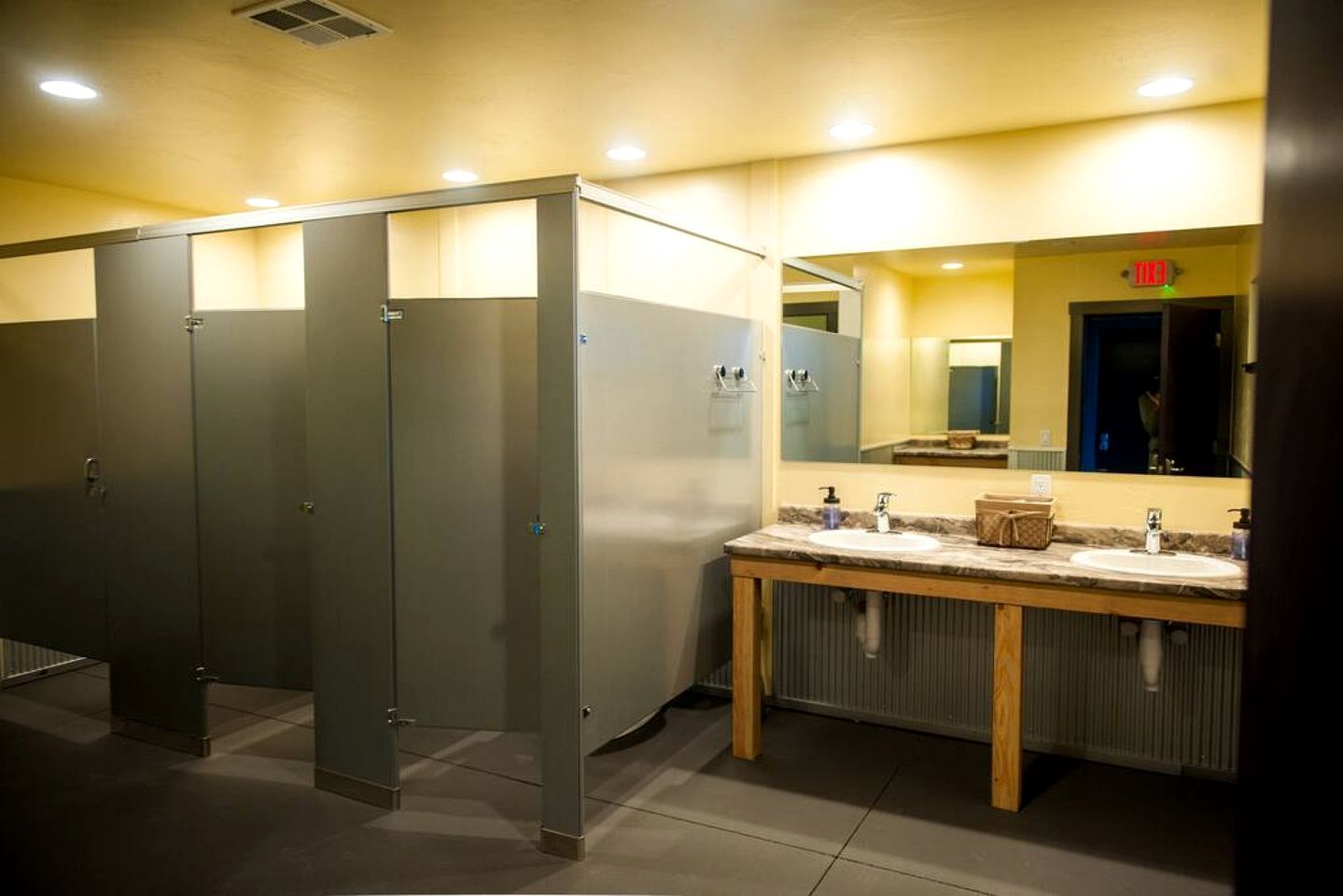 A public restroom with multiple stalls, a sink area, and a mirror.