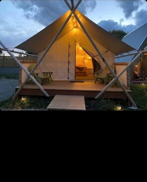 A tent with a wooden deck and a single table.
