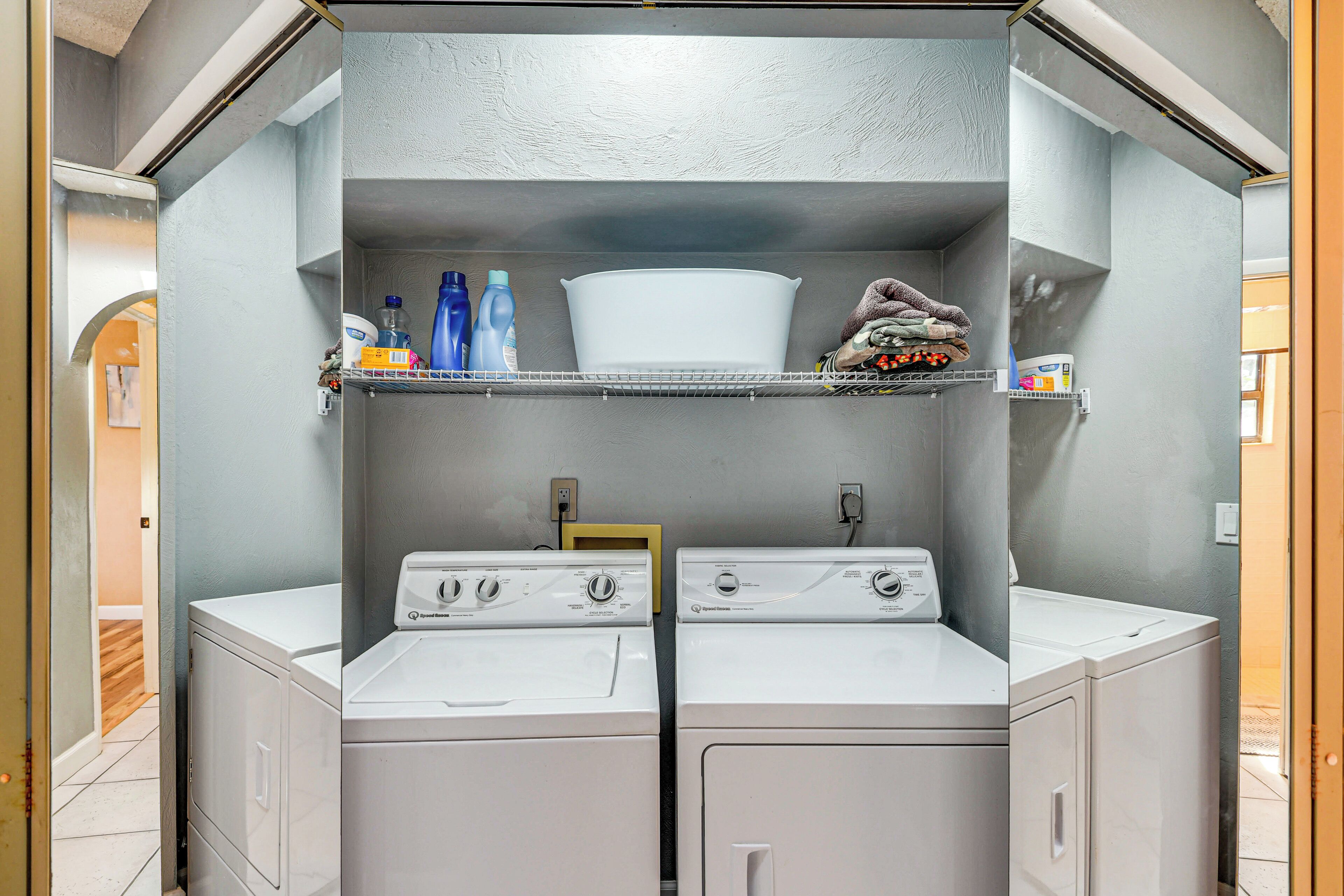 A laundry room with two washing machines, shelves with cleaning supplies, and a white basin.
