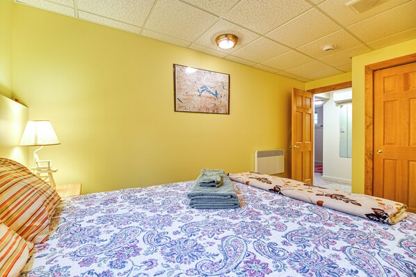 A hotel room with a bed, a nightstand, a lamp, a door, and a hallway. - Air-conditioned Hideaway Near Sugarloaf Mountain (Kingfield)