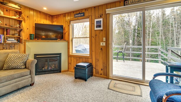 A cabin interior with a fireplace, a sofa, a television, and a sign reading "Welcome to the Cabin."