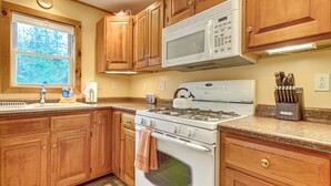 A kitchen with wooden cabinets, a white stove, a microwave, and a granite countertop.
