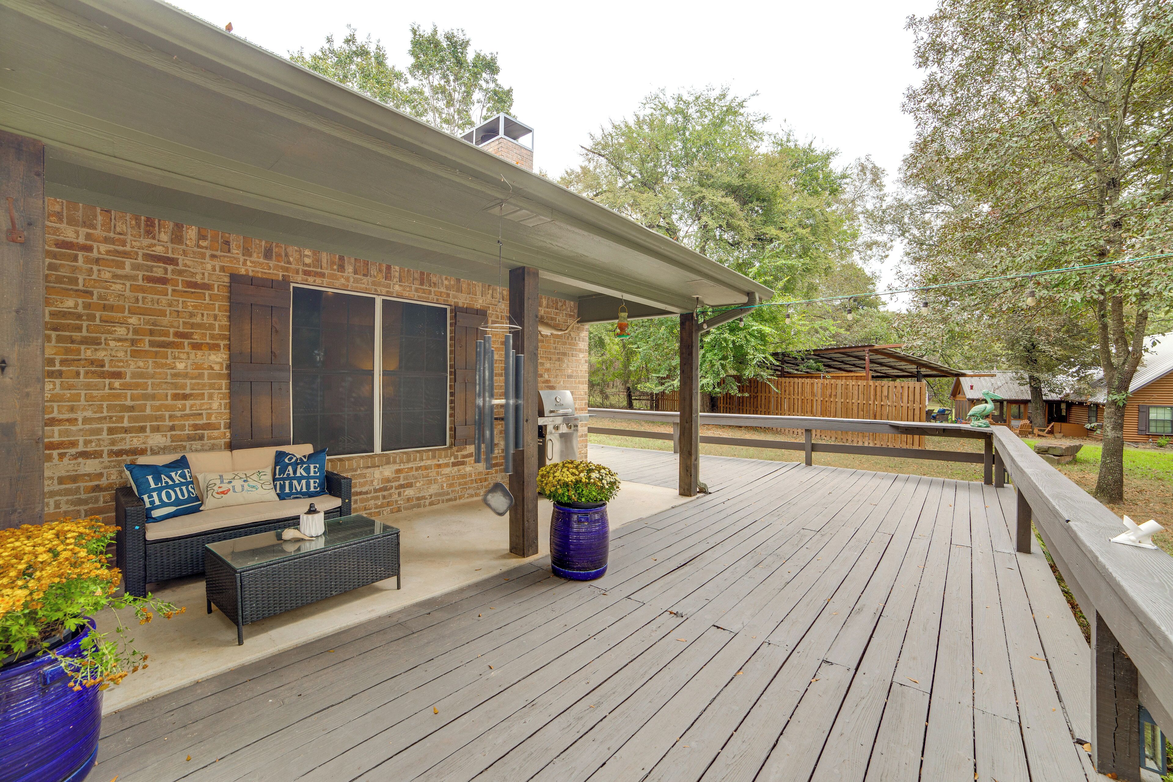 Un patio cubierto con fachada de ladrillo, una terraza de madera y mobiliario exterior.