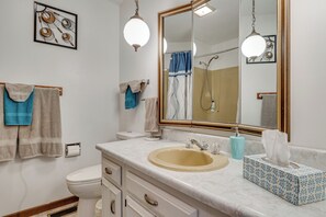 A bathroom with a sink, mirror, towel rack, toilet, and a shower area.