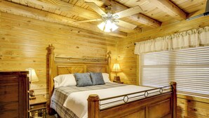 Camera da letto in legno con letto, comodino, lampada e ventilatore a soffitto.