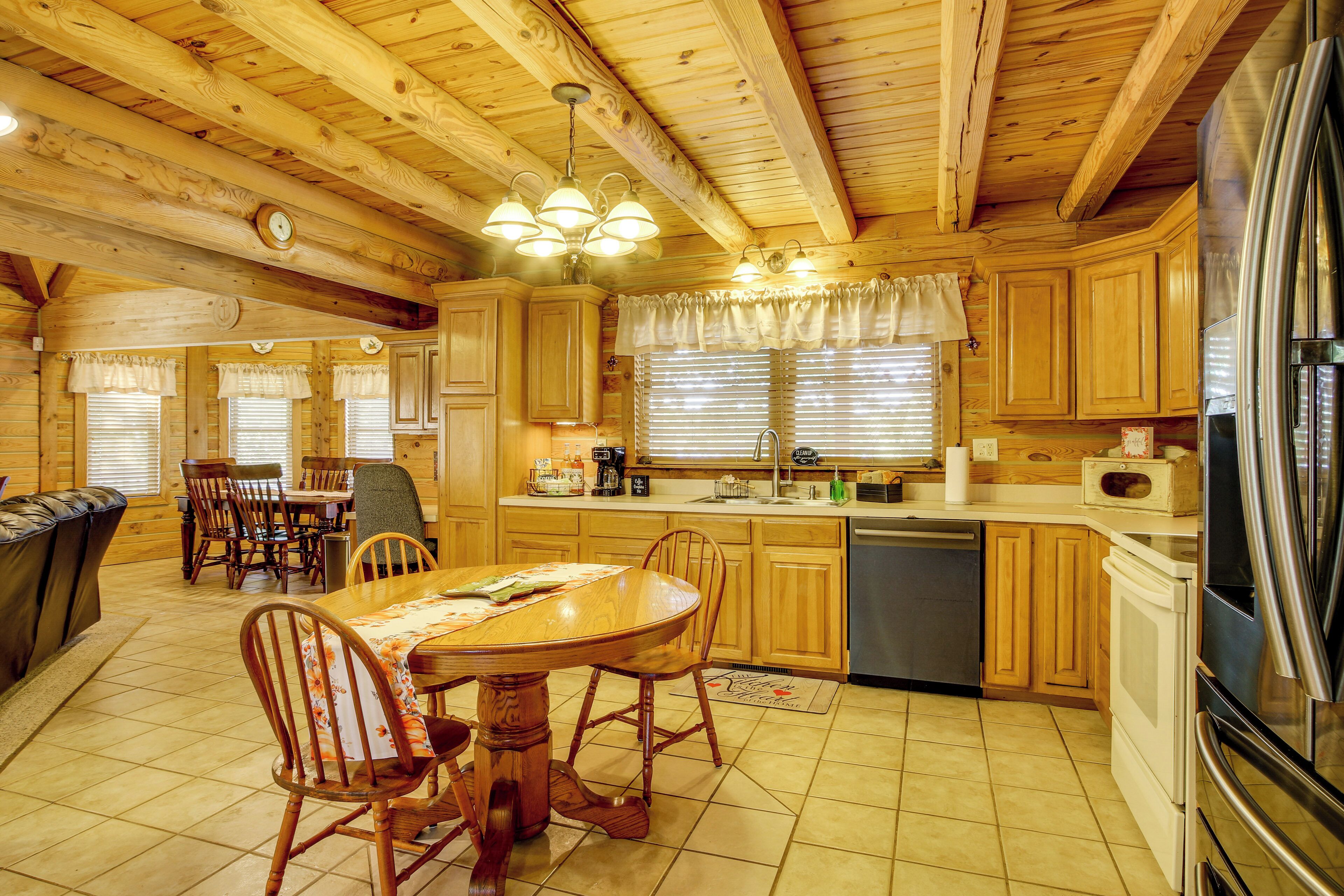 A wooden cabin interior with a dining area, kitchen, and a large refrigerator.