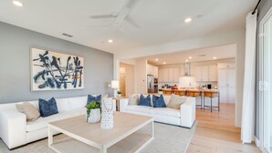 A modern living room with a white sofa set, a coffee table, and a large abstract painting. - Elegant & Spacious Retreat w/ Yard in Woodland! (Woodland)