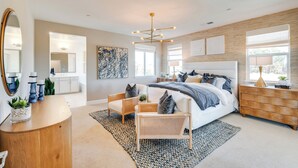A modern bedroom with a large bed, a wooden dresser, a mirror, and a small seating area. - Elegant & Spacious Retreat w/ Yard in Woodland! (Woodland)