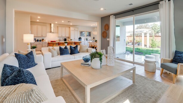 A spacious living room with a white sofa, a coffee table, and a view of the kitchen and backyard through large sliding glass doors. - Elegant & Spacious Retreat w/ Yard in Woodland! (Woodland)