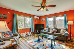 A living room with a ceiling fan, a television, a sofa, a coffee table, and a lamp.