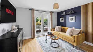 En moderne stue med sofa, sofabord og fjernsyn ophængt på væggen.