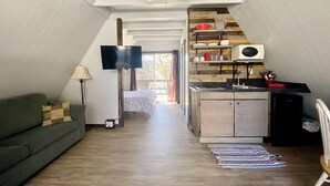 Ein Loft-Zimmer mit Küchenzeile, einer Couch, einem Fernseher und einem Deckenventilator.