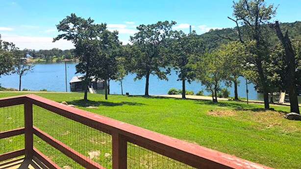 Ein Rasen mit einer Holzterrasse und Blick auf einen See.