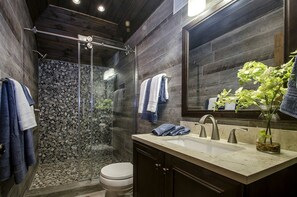 A modern bathroom with a glass-enclosed shower, a marble sink, and a large mirror.
