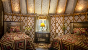 A yurt with two beds, a window with a lamp, and a small table with a plant. - Creekside Secluded Yurt with Jacuzzi in Topton, North Carolina (Topton)