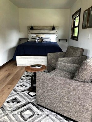 Ein gemütlicher Raum mit Bett, Schlafsofa, kleinem Tisch und einem gemusterten Teppich.