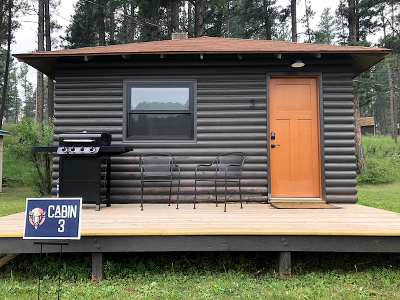 A cabin with a grill, a door, and a window.
