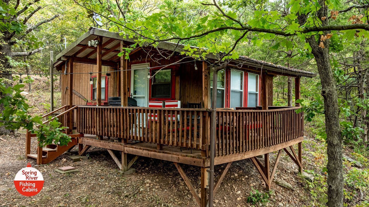 Una baita di legno con una veranda, circondata da alberi.
