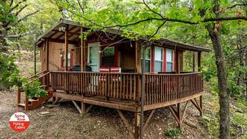 Una baita di legno con una veranda, circondata da alberi.