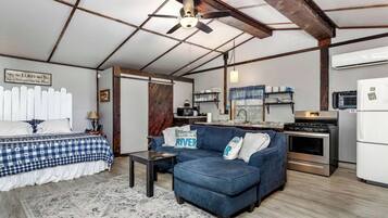 A compact living space with a bed, sofa, and kitchenette.