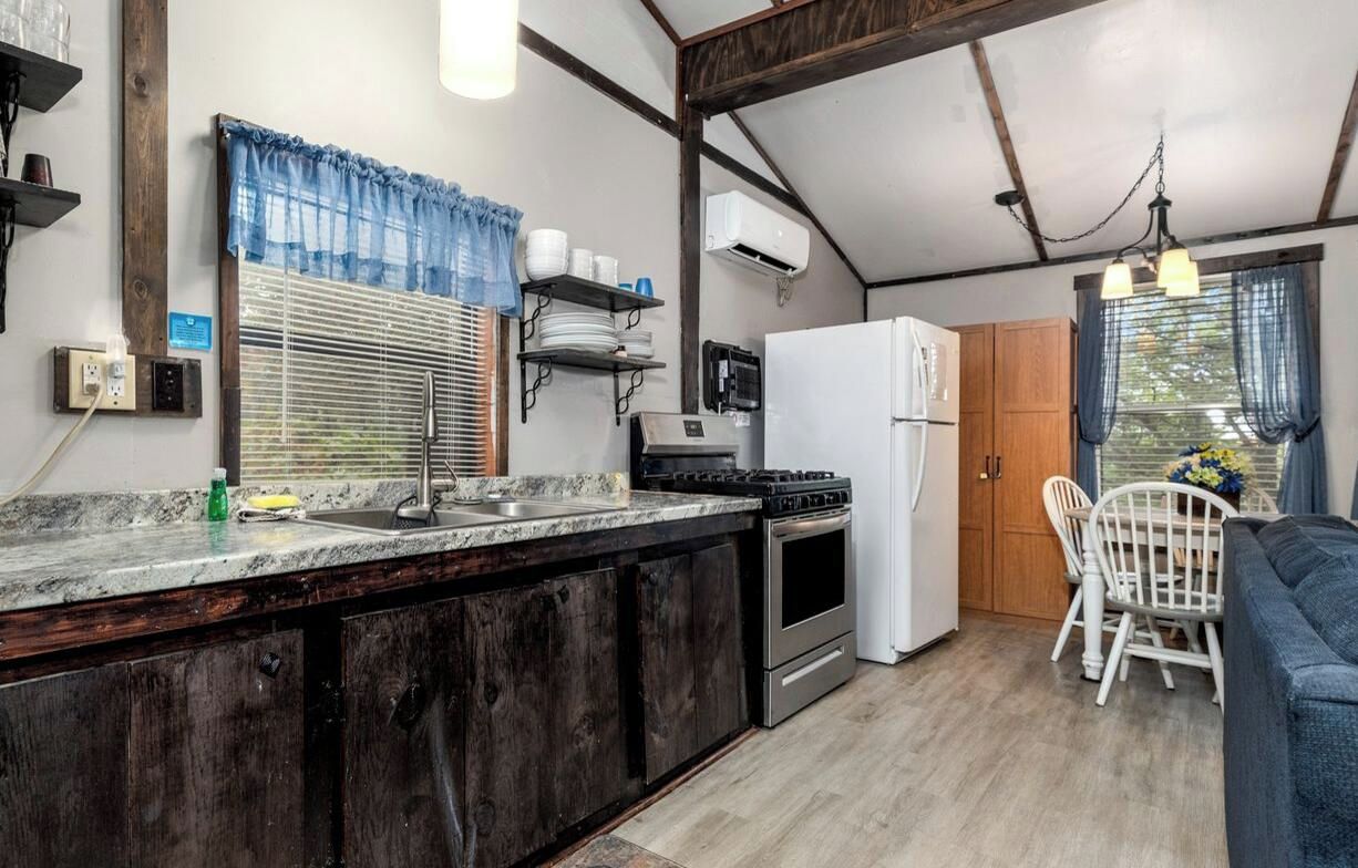 A compact kitchen with a stove, refrigerator, and a dining area with a table and chairs.