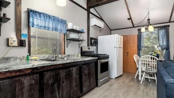 A compact kitchen with a stove, refrigerator, and built-in oven. There is a dining area with a table and chairs.