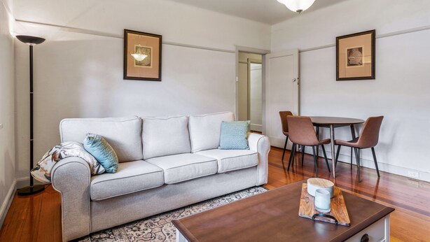 Een moderne woonkamer met een bank, salontafel en eethoek.