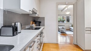 Een moderne keuken met grijze tegels, roestvrijstalen apparatuur en een houten vloer.