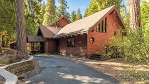 Een chalet met een schuin dak, een veranda en een pad van stenen dat naar de ingang leidt.