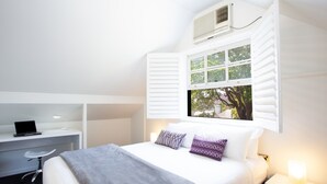 A bedroom with a bed, a desk, a chair, a window with shutters, and a nightstand. - Woolwich Studio Bliss, Private Oasis by the Water (Sydney)