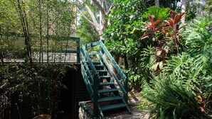 A wooden staircase leading up to a bridge in a lush garden with various plants and trees. - Woolwich Studio Bliss, Private Oasis by the Water (Sydney)