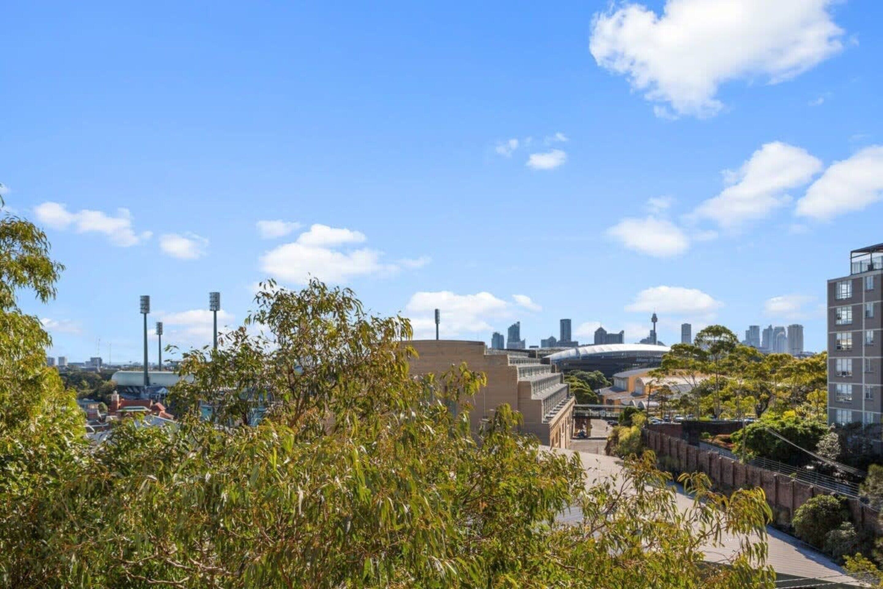 A cityscape with modern buildings, a stadium, and a clear blue sky.