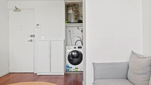 Une petite buanderie équipée d’un lave-linge, d’un sèche-linge et d’un chauffe-eau.