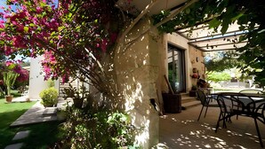 Un patio cubierto con una mesa y sillas, una planta en maceta y una pared con una ventana.