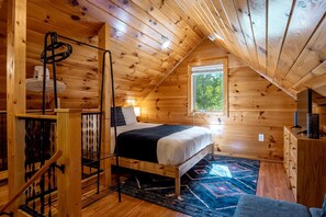 Ein gemütliches Schlafzimmer im Dachgeschoss mit Bett, Fenster und Holzwänden.