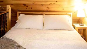 Um quarto com painéis de madeira, uma cama, uma mesa de cabeceira e uma luminária.