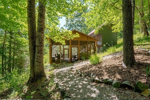 A wooden cabin with a porch, surrounded by trees and a gravel path. - Tiny Luxury Getaway: Cabin in Todd, North Carolina with Hot Tub, Scenic Views, and Lounge Perfection (Todd)