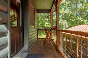 A wooden porch with a table and chairs, overlooking a wooded area. - Tiny Luxury Getaway: Cabin in Todd, North Carolina with Hot Tub, Scenic Views, and Lounge Perfection (Todd)
