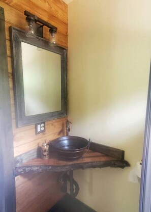 Une salle de bain avec un meuble-lavabo en bois, un miroir et un lavabo sur colonne.