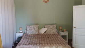 Ein Schlafzimmer mit einem Bett, Nachttischen, einer Lampe, einem Sessel und einem Kleiderschrank.