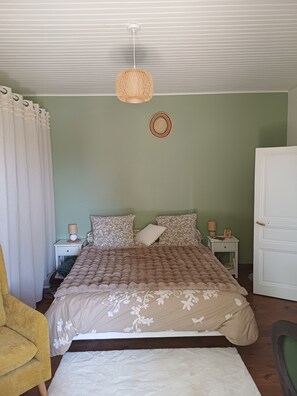 Ein Schlafzimmer mit einem Bett, Nachttischen, einer Lampe, einem Sessel und einem Kleiderschrank.
