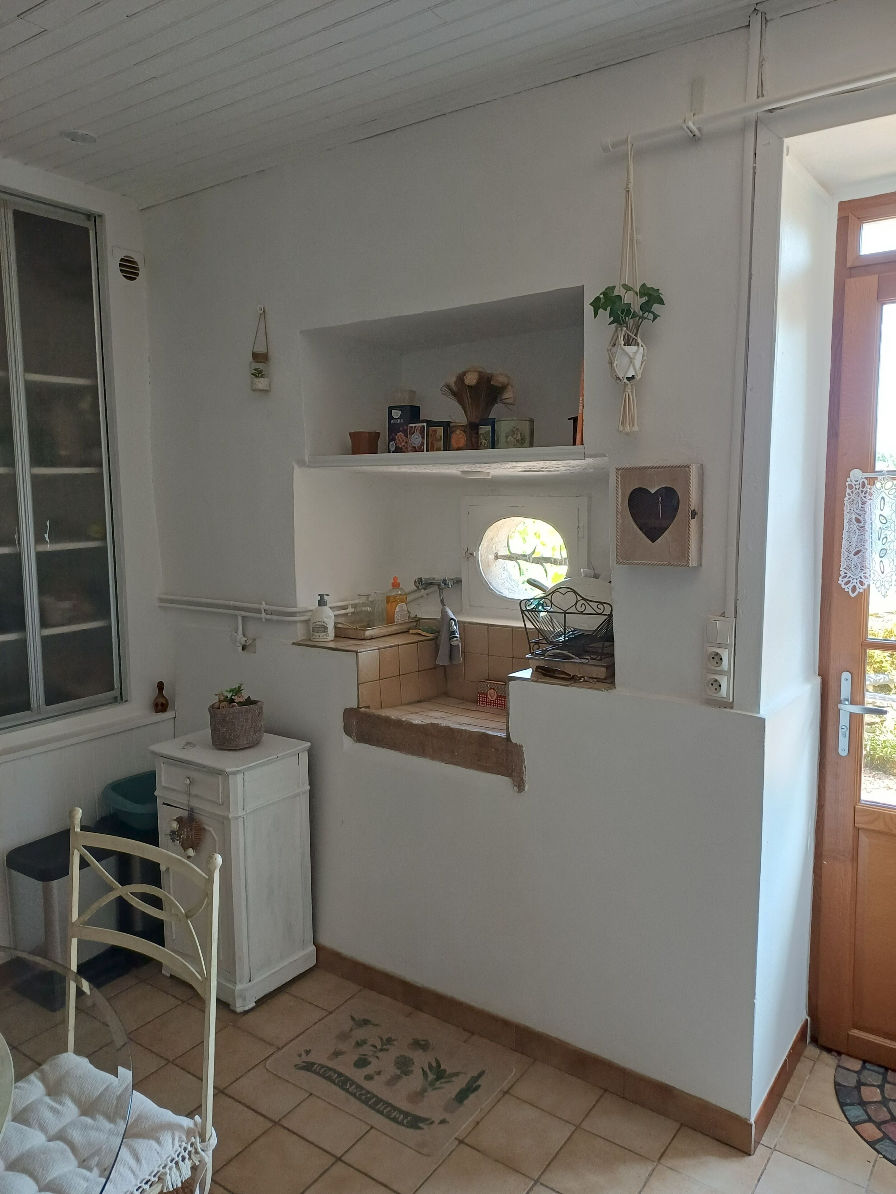 A compact kitchen with white cabinetry, a small countertop, and a window.
