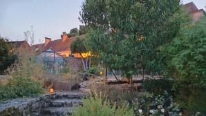 Ein Garten mit Steintreppen, blühenden Pflanzen und einem Gewächshaus.