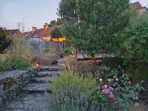 Ein Garten mit Steintreppen, blühenden Pflanzen und einem Gewächshaus.