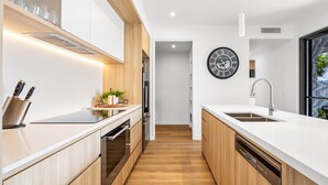 A modern kitchen with wooden cabinets, a built-in oven, and a sink. - Bokarina 3-bed Stunning Home, Steps From Beach (Sunshine Coast)