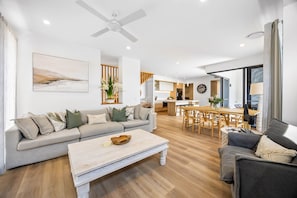 A modern living room with a sofa, coffee table, and dining area. - Bokarina 3-bed Stunning Home, Steps From Beach (Sunshine Coast)